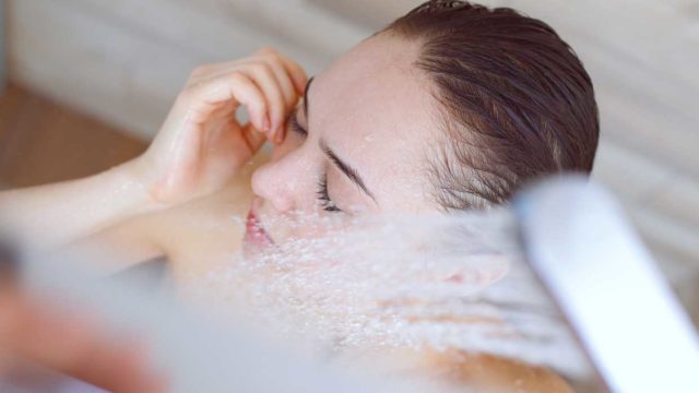Young beautyful woman under shower in bathroom.